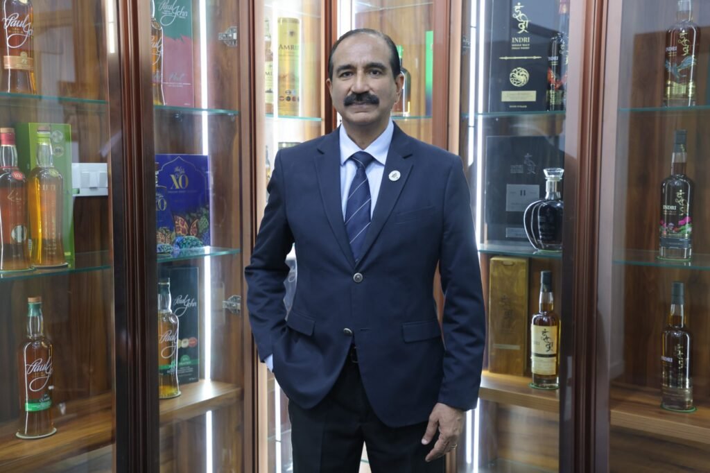 Maj Gen (Dr) Rajesh Chopra, AVSM (Retd), IGSA judge, standing in front of a display of Indian single malt whiskies